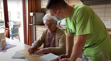 Auszubildender Pflegefachmann unterstützt Seniorin bei der Hausarbeit im Pflegeheim