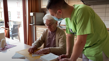 Auszubildender Pflegefachmann unterstützt Seniorin bei der Hausarbeit im Pflegeheim